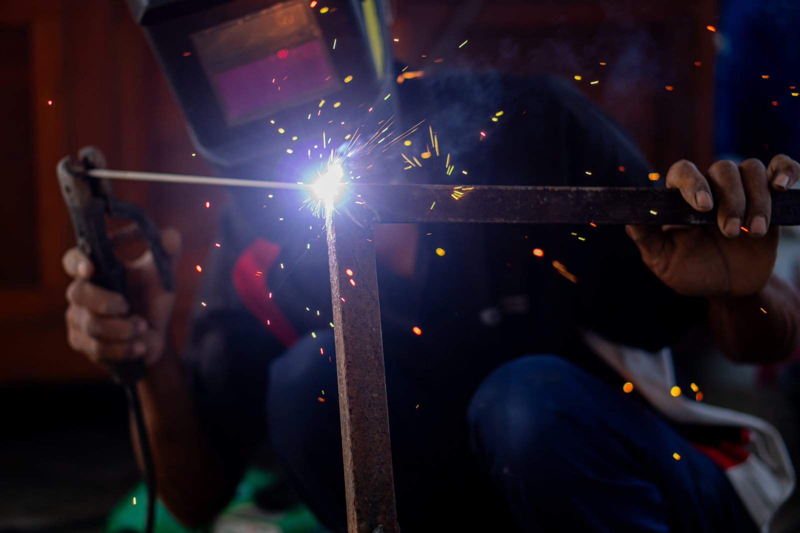 Welder working on a metal frame with protective equipment.