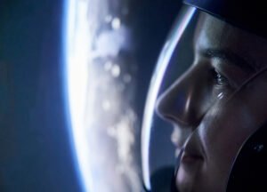 Close-up of an aspiring astronaut in a space helmet looking out at Earth